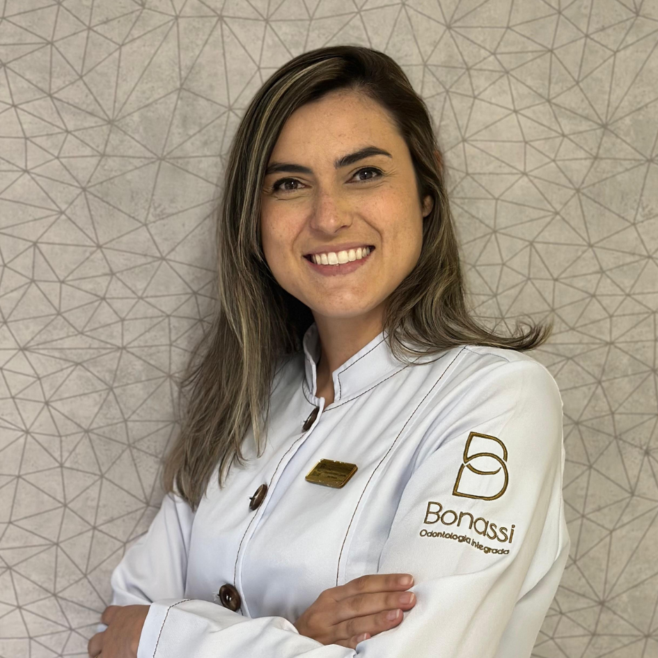 Doutora Isabela sorrindo de jaleco branco e braços cruzados