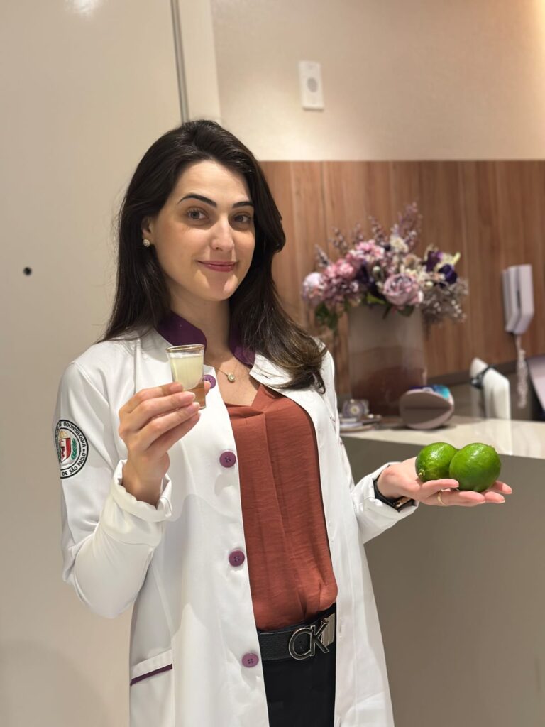 Doutora Maisa segurando 2 limoes na mao esquerda e um copinho do shot na mao direita