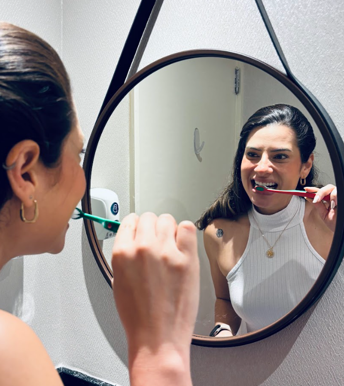 Mulher escovando os dentes em frente ao espelho