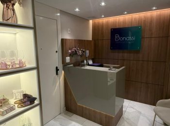 Balcao da recepçao da Bonassi Odontologia com estante à esquerda com filtro de água e cafeteira